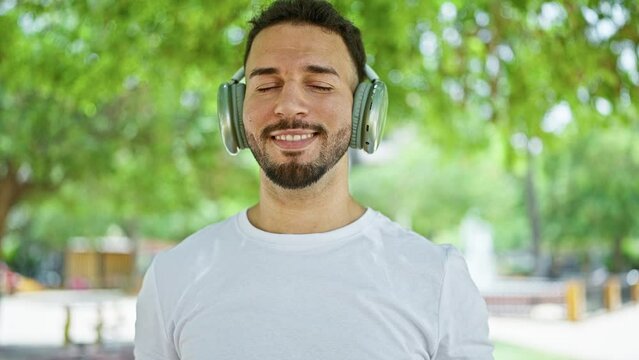 Young arab man listening to music smiling at park
