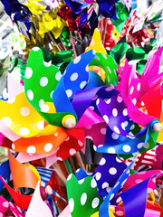 Fototapeta na wymiar Numerous colorful toy windmills in a very large display stand