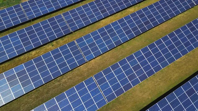 Sonnenschein und Reflexionen auf den blauen Solarmodulen eines modernen Solarparks auf einem Feld in einer ländlichen Gegend in Deutschland