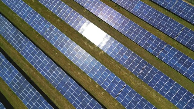 Drohne, die in einem Bogen fliegt, w&auml;hrend sie auf einen Solarpark mit Solarmodulen auf einer l&auml;ndlichen Wiese mit Sonnenschein zoomt, Deutschland