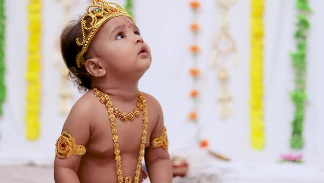 adorable infant dressed as hindu god krishna cute facial expression playing at tree at janmashtami