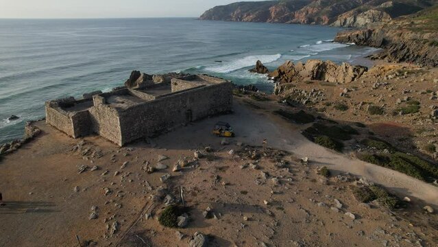 Aerial drone view of an yellow tuk-tuk rickshaw parked outside the Fort of Guincho near Abano Beach in Guincho, Cascais, Portugal
