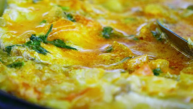 An extreme close-up of traditional Bahian moqueca, simmering in a rich blend of coconut milk and palm oil, showcasing the authentic flavors of Bahia, Brazil. 