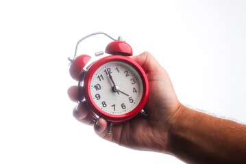 Beautiful red alarm clock in hand on a white isolated background.