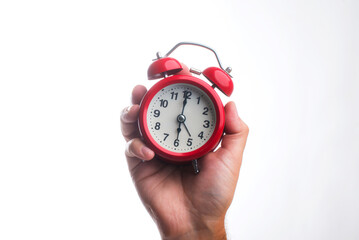 Vintage red alarm clock in hand.
Round red alarm clock on a white background shows 6 am