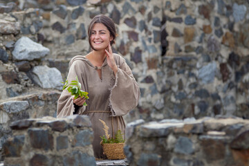 Pretty friendly market woman in the Middle Ages sells herbs