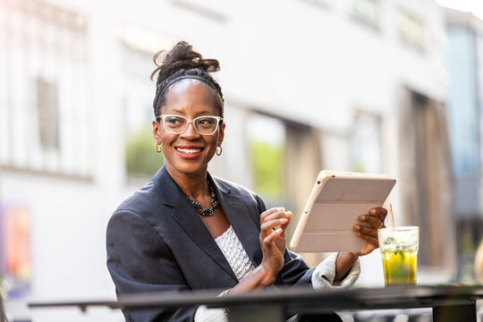 Portrait Of Happy Businesswoman Using Tablet Computer In Outdoor Cafe
