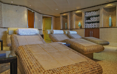 Thermal suite with heated loungers in mosaic tile design or relaxation chairs in spa or wellness...