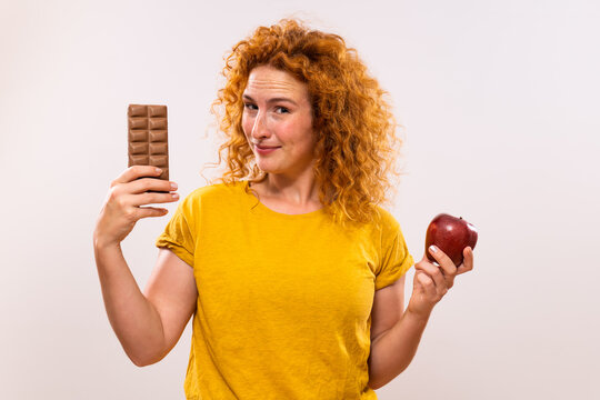 Cute ginger  woman having doubts with healthy and unhealthy eating.