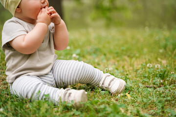 Charming baby child sitting on the shore of the lake on the grass in summer