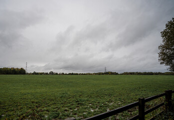 Cloudy sky over a green field in Enlgand with cows and electric pylons