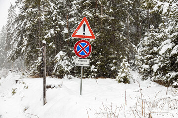 View of exclamation and no stopping sign in Misurina in a snowstorm winter day; Province of Belluno, Dolomites, Italy