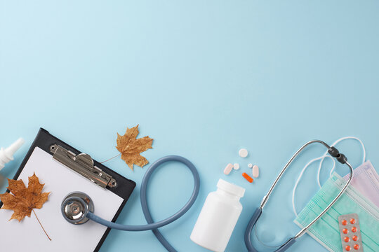 Discover the doctor appointment concept. Top view photo of stethoscope, medical masks, autumn leaves, drugs, clipboard on light blue background with advert zone