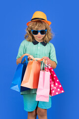 Discounts and sales. Happy child with shopping bags. Kid with shopping bags posing on blue studio isolated background. Trends and brands.