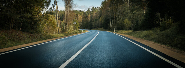 Riga - Valmiera asphalted new road. Road traffic on Latvian roads. Road with asphalt coating. Heavy and light vehicle movement. - obrazy, fototapety, plakaty