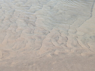 Abstract sand patterns under a thin layer of water