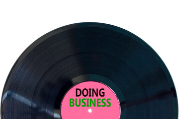 Doing business symbol. Concept words Doing business on beautiful black old retro vinyl disc. Beautiful white table white background. Business, motivational Doing business concept. Copy space.