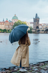 A traveler woman  enjoys the view over the Vlatava River to the Charles Bridge and castle of Prague, Czech Republic - 661593530