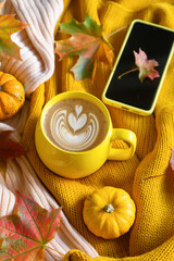 A cup of coffee and a phone on the table among pumpkins and autumn leaves. Calendar for 2024.
