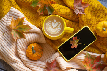 A cup of coffee and a phone on the table among pumpkins and autumn leaves. Calendar for 2024.