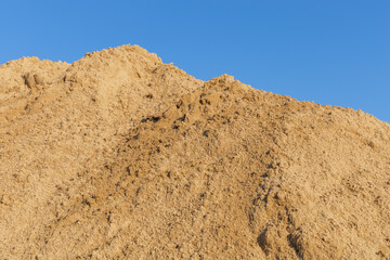 Perfect clean sand against the blue sky. Material for construction work. Mountain of sand or dune on a sandy beach. Vacation concept. Construction concept