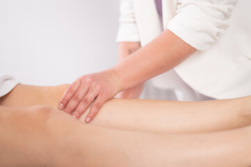 Obraz na płótnie Canvas Crop massage therapist massaging knee of client