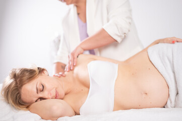 Tranquil lady getting neck massage during pregnancy in salon
