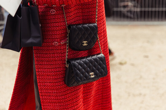Closeup of black handbags, woman walking on the street wearing a red outfit - Chanel Paris Fashion Week Street Style