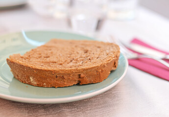 Large cut of organic whole grain bread on green ceramics plate. Selective focus - Powered by Adobe