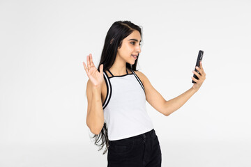 Young Indian girl using a phone or smartphone, talking selfie or talking on video chat on a white background