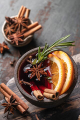 Mulled wine in ceramic mug with orange slices and spices top view. Christmas hot drink on wooden table with xmas tree branches, festive card