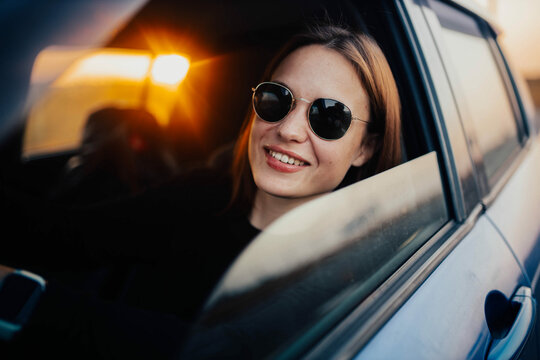 positive woman driver on a journey driving a car. Joyful woman on a car trip, car rental and taxi concept.	