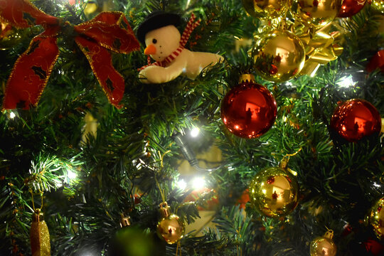 Full frame of Christmas tree decorated with golden and red balls, ribbon, and light, Christmas background.