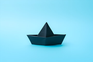 Closeup of a black paper boat on blue background	
