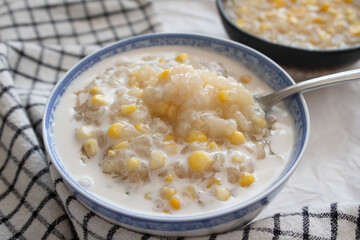 Close up of a bowl of corn and sticky rice pudding dessert with coconut milk.