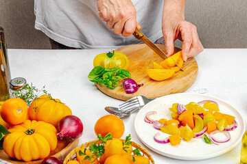 A woman is preparing a tomato salad. Ripe vegetables, herbs, aromatic spices, olive oil