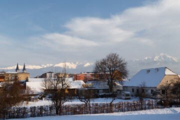 Beautiful winter photo of snow-covered Avrig town with Orthodox church and Carpathian mountains in background, Romania