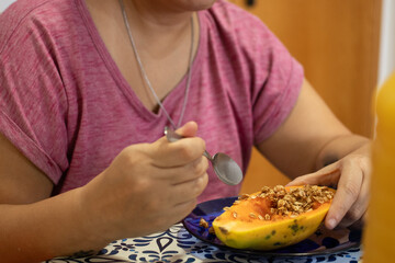 pessoa comendo mamão com granola