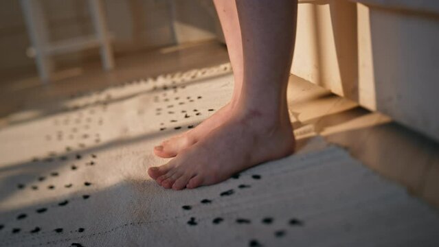 Woman legs stepping bed in sunlight closeup. Unknown woman wake up early morning