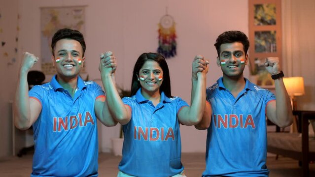 Young Indian cricket fans holding hands and celebrating their cricket team's victory - Indian cricket team  cricket buffs. Young siblings with their faces painted with Indian flags - cheering for I...