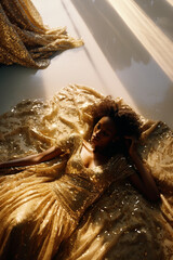 Beautiful fashionable young black woman in golden shiny dress with sequins