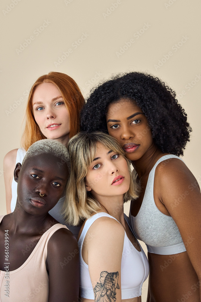 Wall mural Cool fashion gen z girls in underwear looking at camera, beauty portrait. Four confident diverse young women, multicultural ladies international models bonding isolated on beige background. Vertical