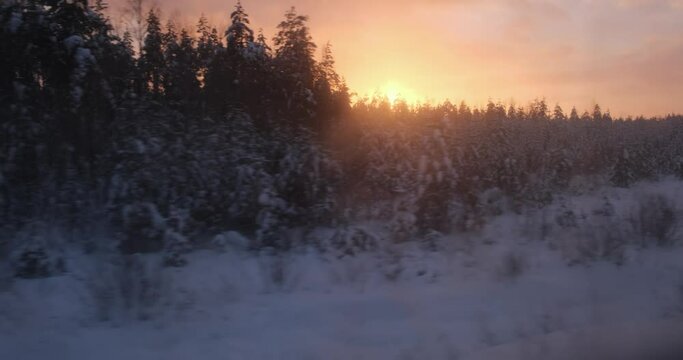 As the sun dips, the train provides a panoramic view of woods, their snowy landscape illuminated by the fading light.