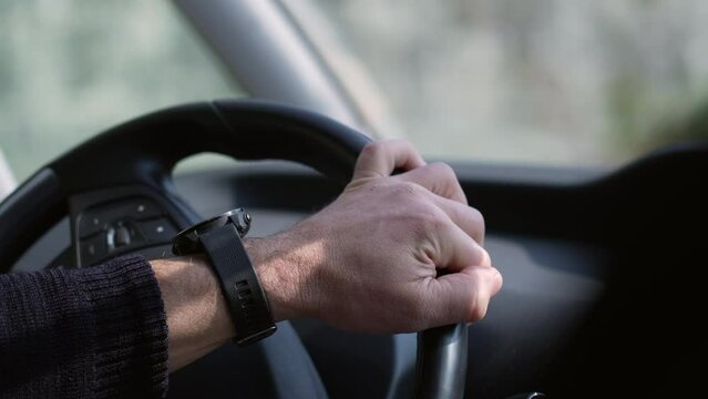 Close-up hand holding vehicle steering wheel driving car on road