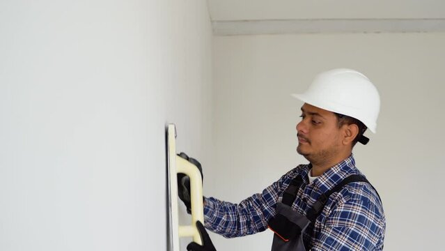 Indian man plasterer construction worker at work with trowel, plastering a wall