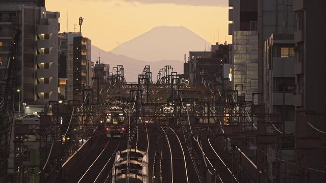 Train traveling on railway track during sunset in Japan, Mt. Fuji view in background. Japanese transportation, Asian commuter lifestyle, Asia tourism
