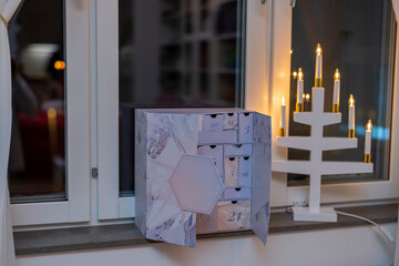 Beautiful interior view of apartment window decorated with advent calendar and traditional electric Christmas candlestick. Sweden.
