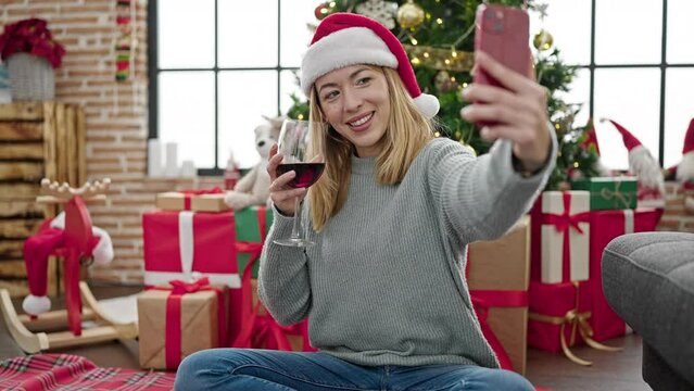 Young blonde woman make selfie by smartphone drinking wine celebrating christmas at home