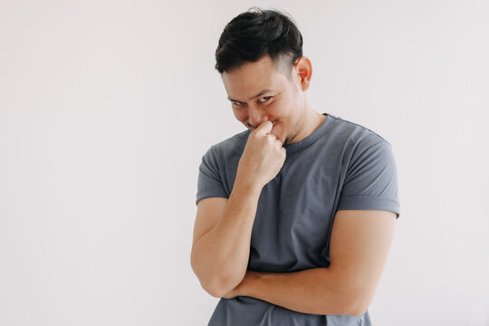 Evil looks of asian man in blue t-shirt smile and smirk stand isolated on white.