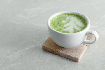 Cup of fresh matcha latte on light grey marble table. Space for text